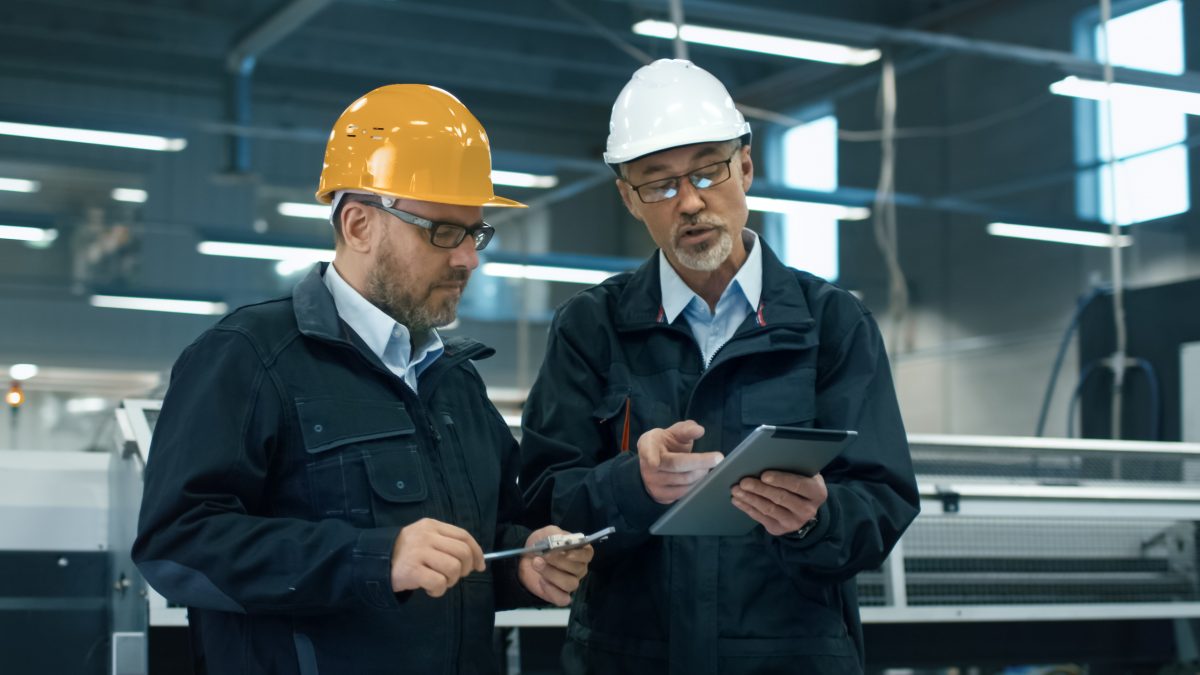 Dos ingenieros con cascos discuten una lista de verificación de cumplimiento de la osha