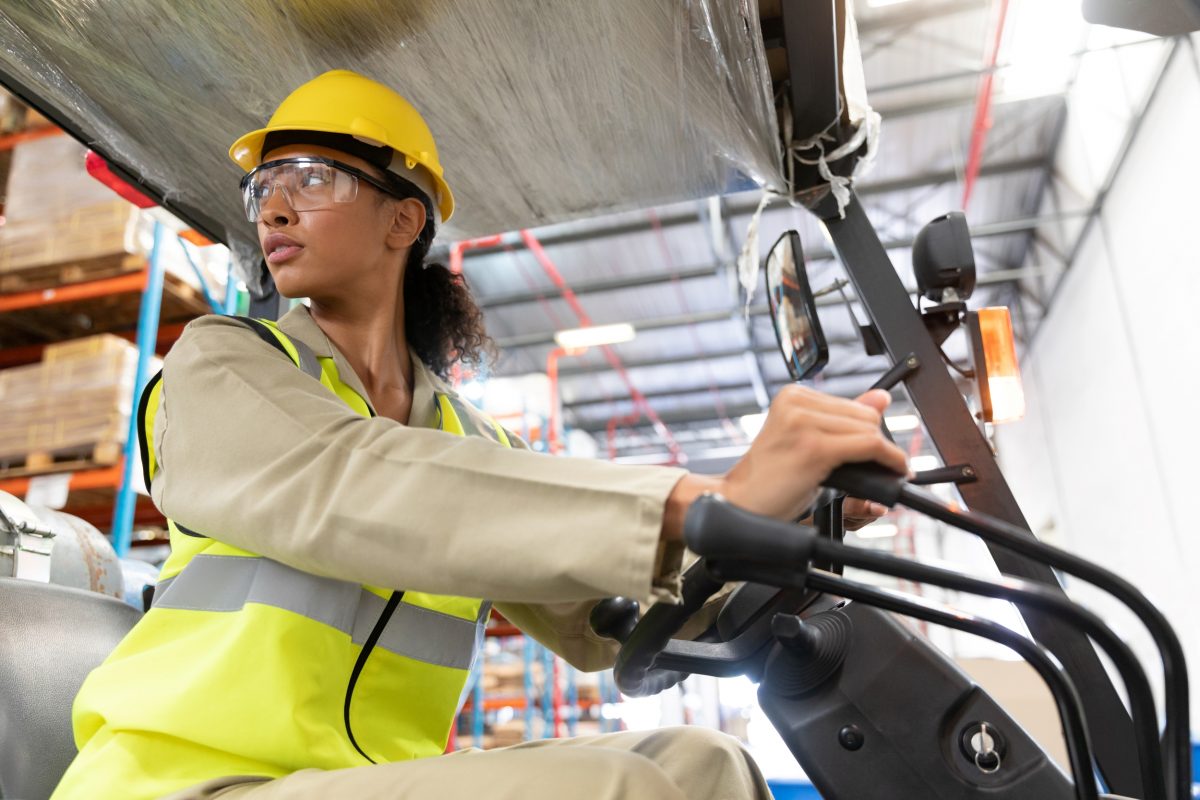 female warehouse worker learning to drive a forklift