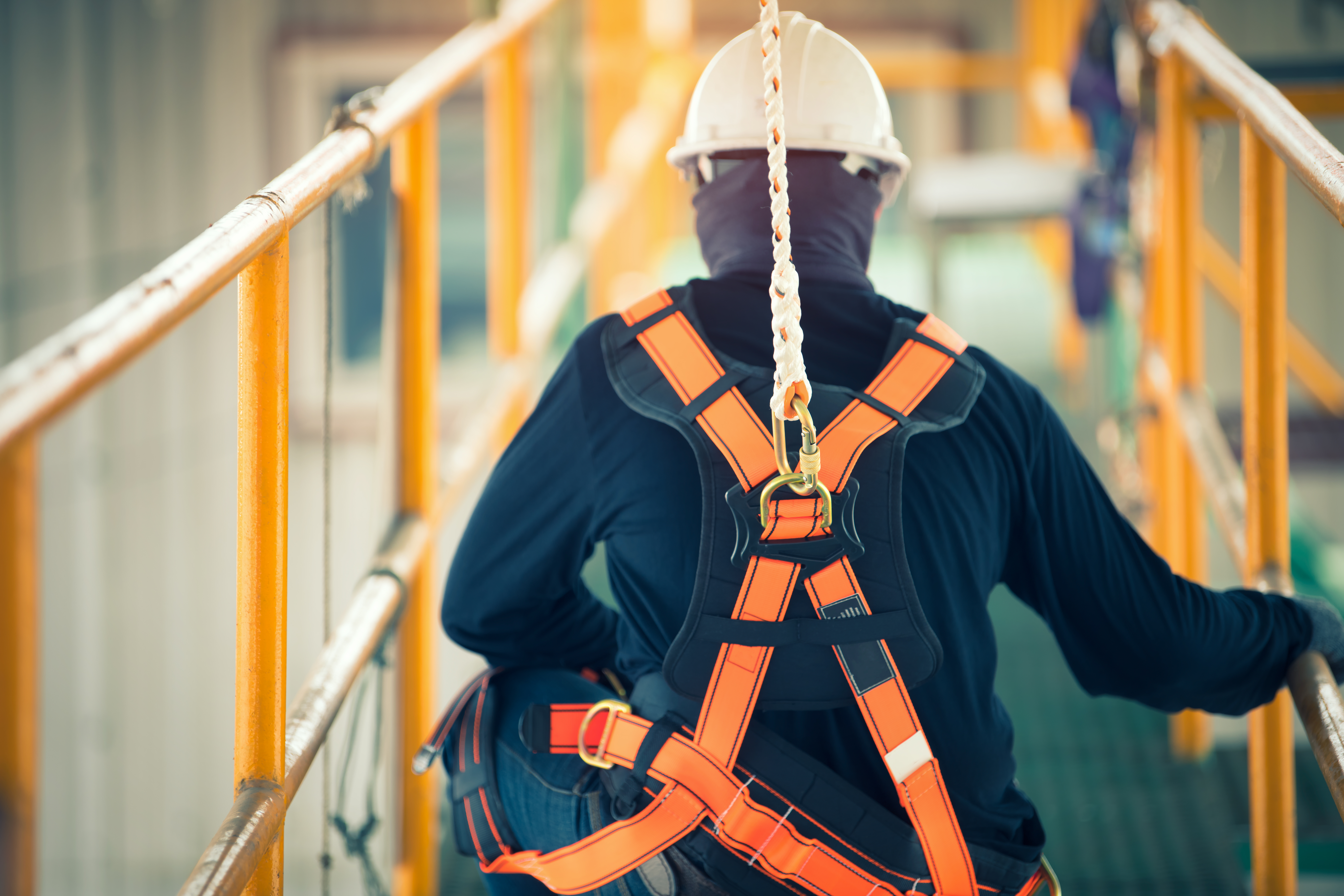 Construction worker following safety management plan wearing harness at heights