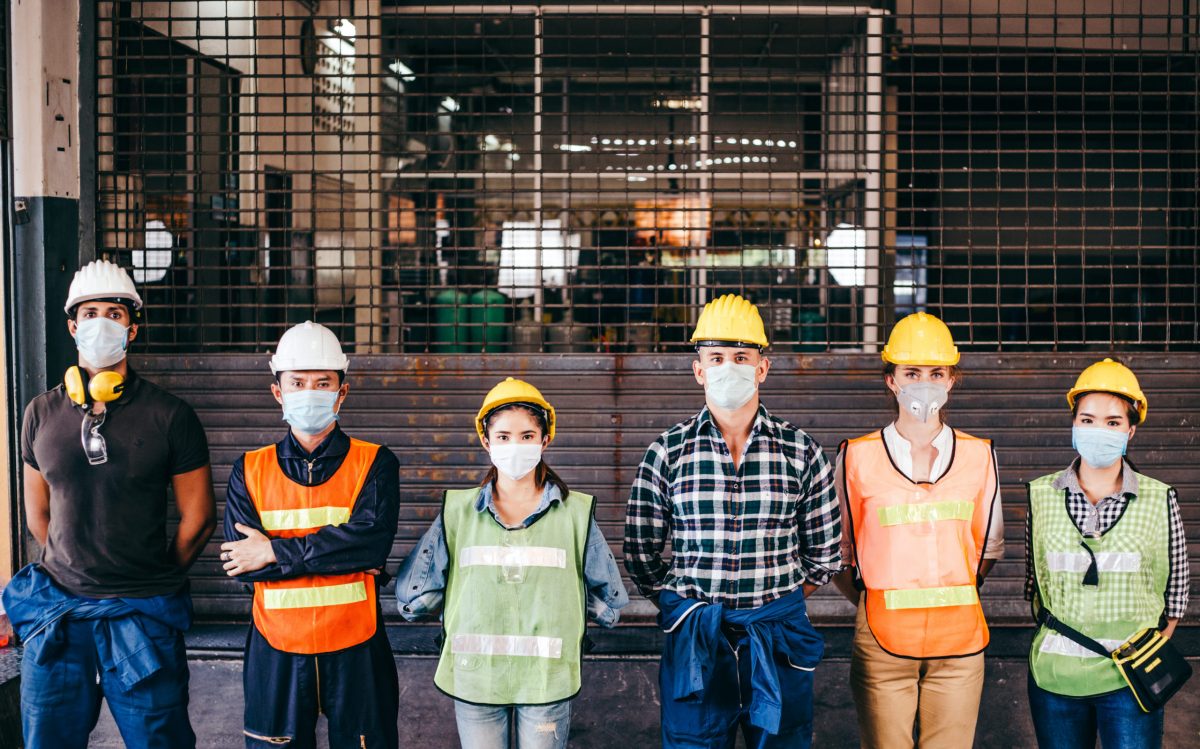 Group Of Industrial Or Engineer Corporate Workers Wear Protective Mask And Hard Hat Helmet Standing Line Up In Front Of Factory Lock Down Prevention For Coronavirus Or Covid 19 Epidemic Outbreak