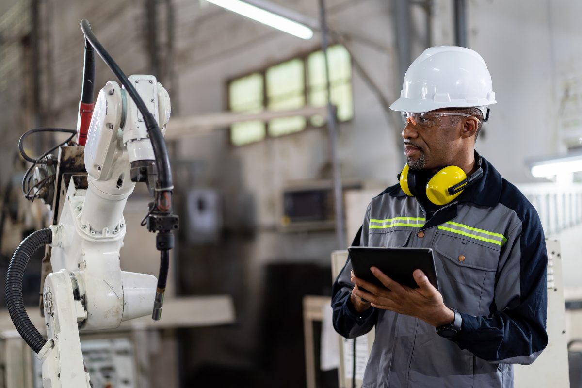 African American Male Engineer Worker Using Digital Tablet Control Automatic Robotic Hand Machine In Factory for Industrial Robotics Safety